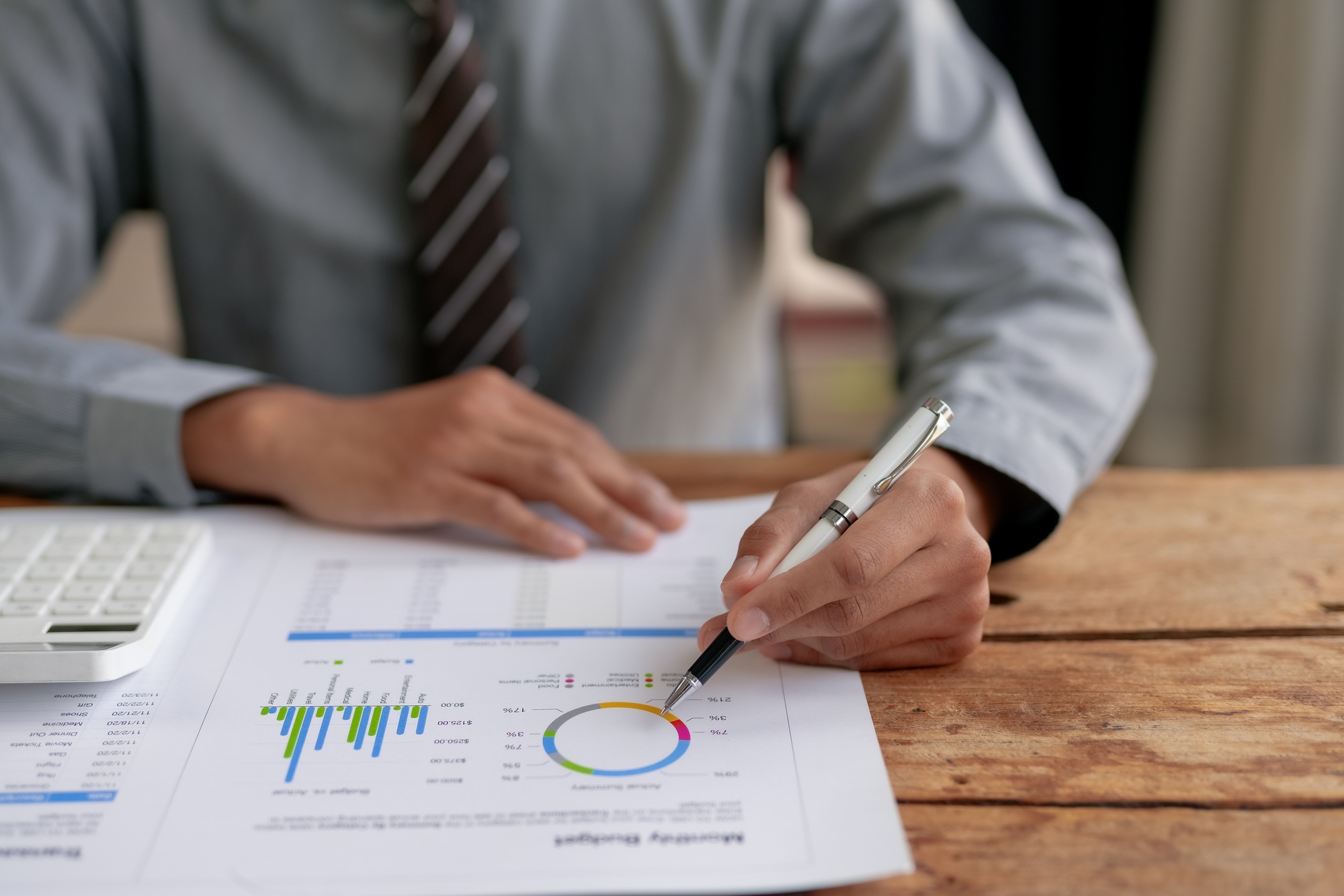 Businessman analyzing financial data and pie chart on a report at the office desk with a pen
